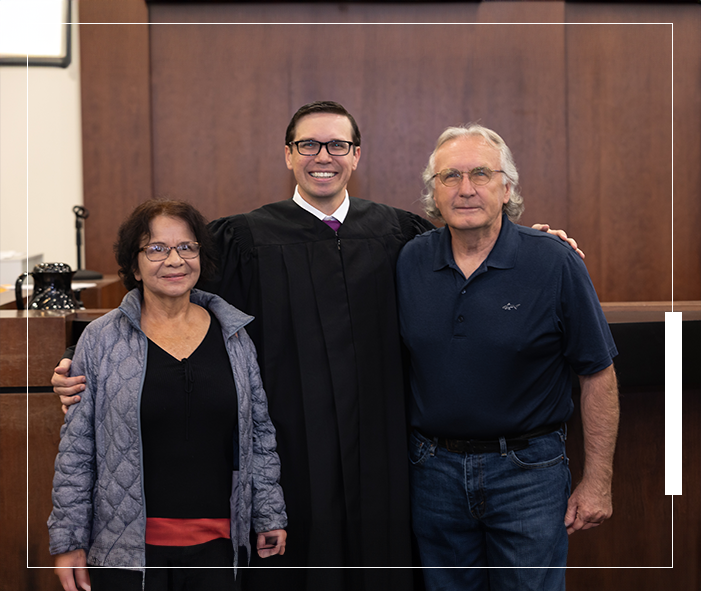 A man in a robe stands between two people.